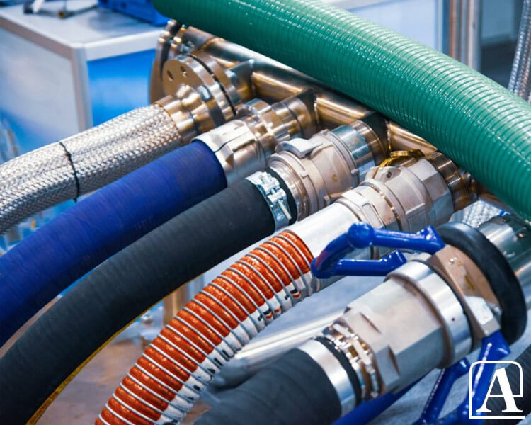 Tuyaux industriels Amiflex de différentes couleurs connectés à des raccords métalliques, avec une vanne bleue en arrière-plan.