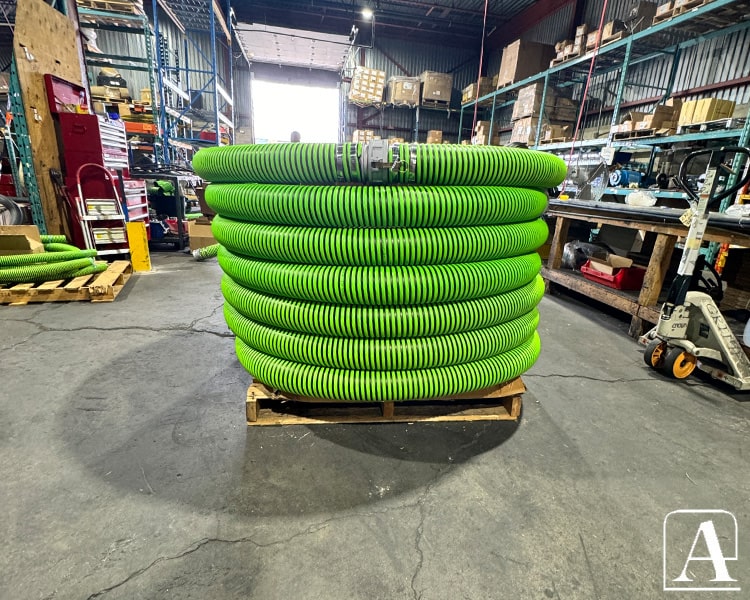 Pile de tuyaux industriels verts Amiflex entreposés, montrant l'ampleur de l'inventaire.