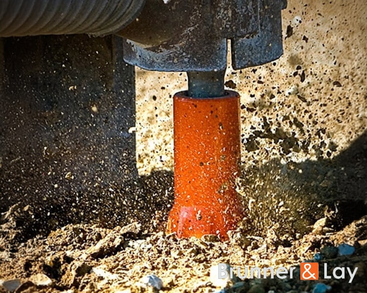 Compacteur de sol Brunner vibrant la terre pour les travaux d'excavation sur un grand chantier industriel.