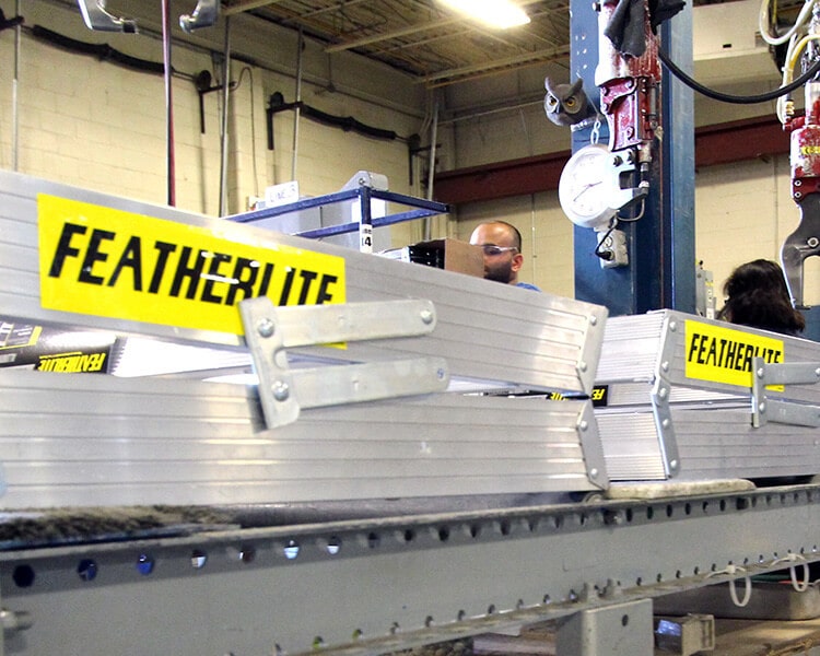Poutres en aluminium Featherlite sur une chaîne de montage industrielle, mettant en avant la fabrication d’échelles Featherlite robustes et durables.