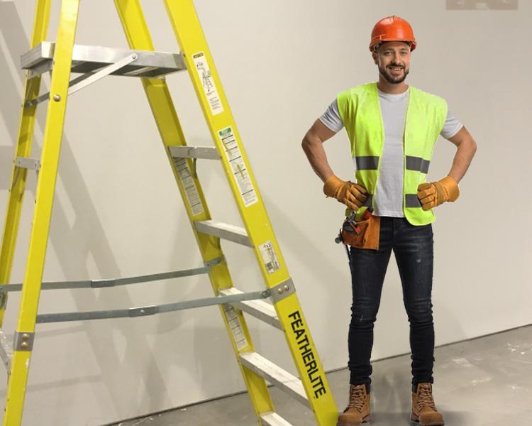 Travailleur de construction en gilet de sécurité positionné à côté d'une échelle Featherlite, démontrant la fiabilité et la sécurité sur chantier.