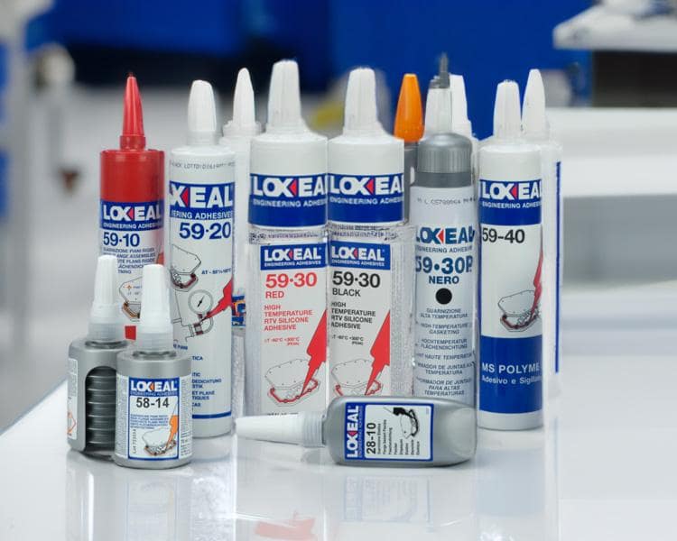 Produits adhésifs Loctite, tubes et bouteilles bien présentés sur une table, avec un fond bleu flou, idéal pour des applications industrielles et de construction.