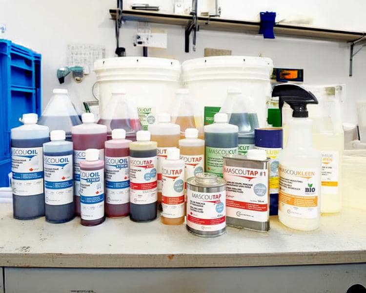 Bouteilles et contenants chimiques étiquetés en français, disposés sur un comptoir de laboratoire, représentant des produits chimiques ou de nettoyage.