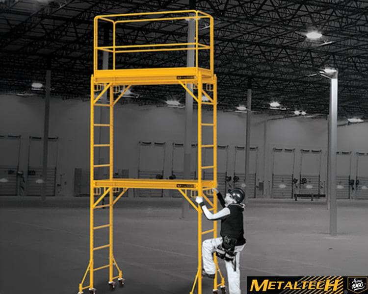 Un travailleur de Metaltech debout sur une échelle dans un bâtiment industriel, entouré de structures métalliques et de machines, soulignant l'expertise en construction.
