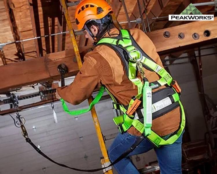 Un ouvrier de construction portant un casque de sécurité et un harnais installe un équipement en hauteur, soulignant l'importance de la sécurité au travail dans un environnement industriel.