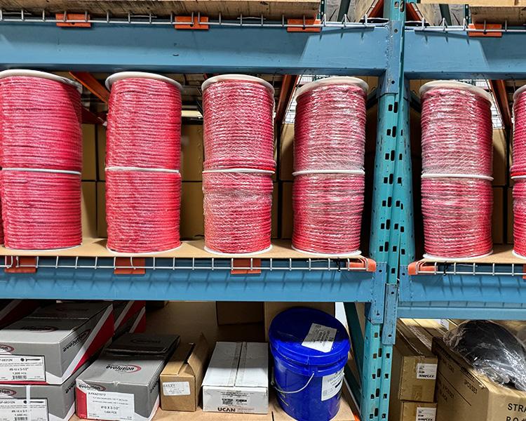 Cordes rouges empilées sur des étagères d'entrepôt, conçues pour des applications lourdes en construction et industrie.