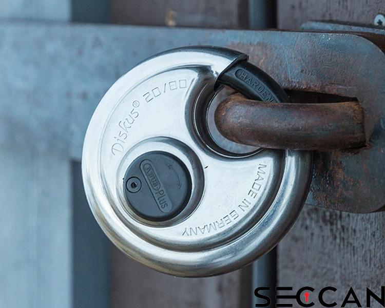 Cadenas ABUS sécurisé sur serrure métallique avec signes d'usure et rouille, logo Seccan visible.